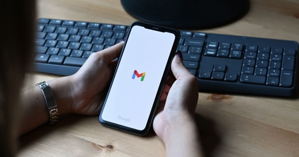 Smartphone tenuto in mano con l'app Gmail aperta — i punti negli indirizzi email Gmail